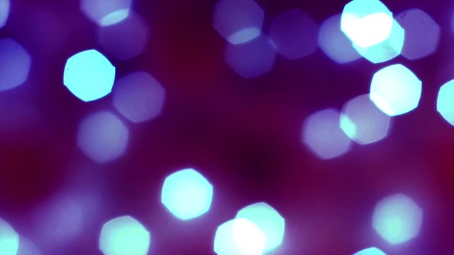 Abstract smooth blue bokeh lights on blurred dark purple background. Bright bokeh effect on defocused sparkling violet background. Holiday spirit. 