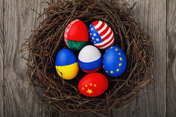 Easter eggs painted in the colors of the flags of different states of the world in the nest, view from above