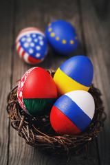 Easter eggs painted in colors of the flags of different states of the world in the nest