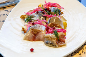 Fish herring with potatoes and red pickled onions.