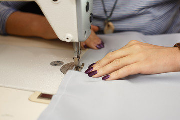 View from above on hands of female tailor working on sewing machine.  dress manufacturing industry