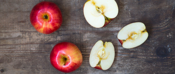 Ripe red apples and slices on dark wooden background, overhead view. From above. Top view, flat lay.