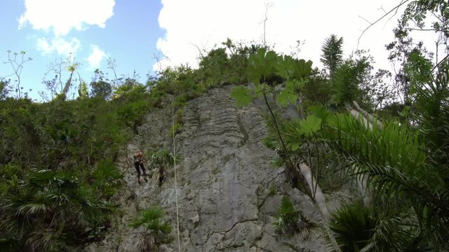 athletic woman rock climbing tropical cliff mountain in Vinales valley, Cuba