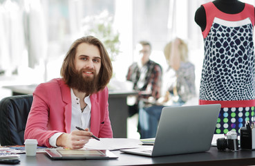 smiling couturier sitting at the table in the Studio