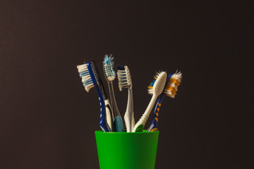 Many toothbrushes in a plastic cup on a black background. The concept of changing toothbrushes, oral hygiene, dentistry. Big and friendly family