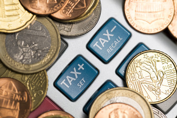 Calculator’s buttons with "tax set” and “tax recall” text surrounded by cash coins, accounting concept