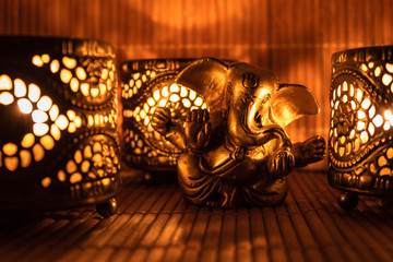 Golden ganesha figure with warm candle light.