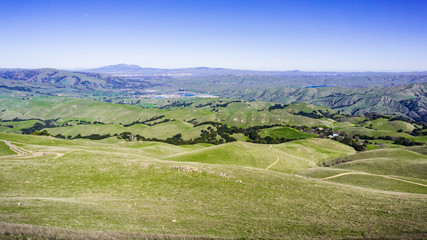 Fototapeta na wymiar Verdant Hills; Mt Diablo and Livermore valley in the background; as seen from the Ohlone Wilderness trail, on the way to Mission Peak, Alameda County, east San Francisco bay area, California