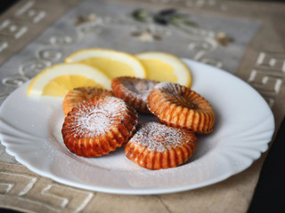 Сurd biscuits and a few slices of lemon in white plate. Linen beige napkin