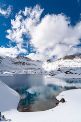 Fototapeta na wymiar A clear blue alpine lake reflects the surrounding snowy mountains