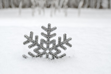 Christmas snowflake in a fluffy, white snowdrift. New Year's holiday toys.