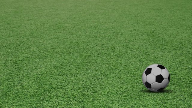 Soccer ball rotating on green football field.