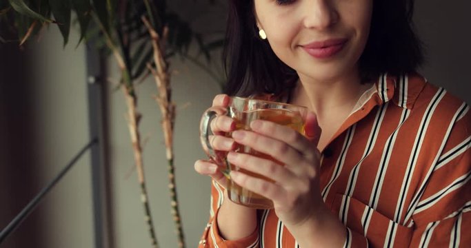 Woman sit on stairs at home, smell her green tea and feels great. Green tree on background and copy space fot text