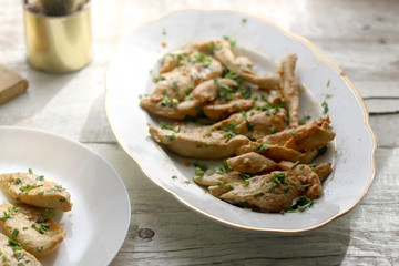 Grilled chicken with fresh parsley on a rustic white table. Selective focus.