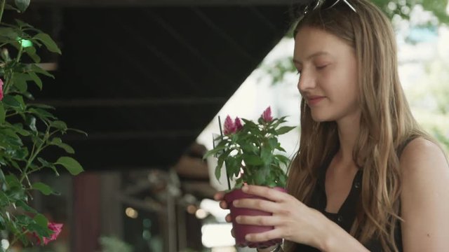 Young woman out for a stroll stops to smell the flowers at an outdoor market in the romantic city of Paris