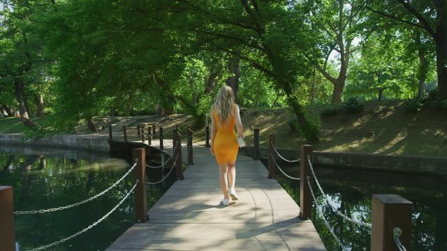 Woman walking on a bridge over a pond
