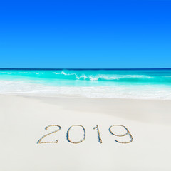 Fototapeta na wymiar Perect white sandy ocean beach and season 2019 handwritten caption on sand