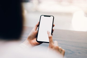 Closeup of woman holding a smartphone, mock up of blank screen. using cell phone on cafe. Technology for communication concept.