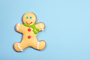 Homemade natural gingerbread man cookie in scarf isolated on light blue paper background. Traditional winter holidays christmas and new year sweet dessert. Copyspace