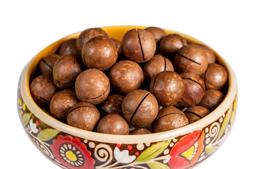 Fresh organic peeled macadamia nuts in ceramic bowl isolated on white