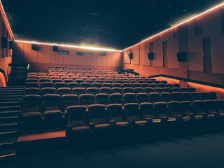 Movie theater with many red seats or chairs in dark empty auditorium