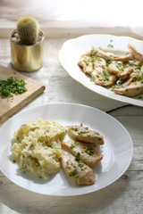 Grilled chicken with fresh parsley and mashed potatoes on a rustic white table. Selective focus.