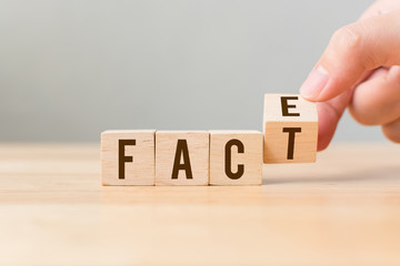 Face to Facts concept. Hand flip over wooden cube block