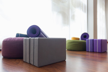 Variety of yoga props on studio wooden floor. Set of blocks, straps on meditation cushions and mat....