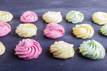 set of colored meringues on black wooden background. geometric pattern.