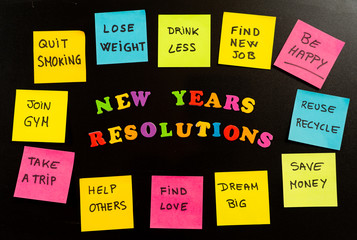 Colorful New Year resolutions and sticky post its notes with popular goals on chalk blackboard