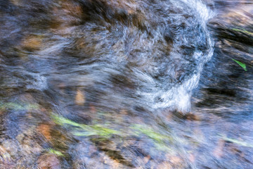 Water stream on a river at South of Chile, an amazing natural textured pattern of the water going down trying to find an exit to the Pacific Ocean while walking through the rocks in a nature scenery