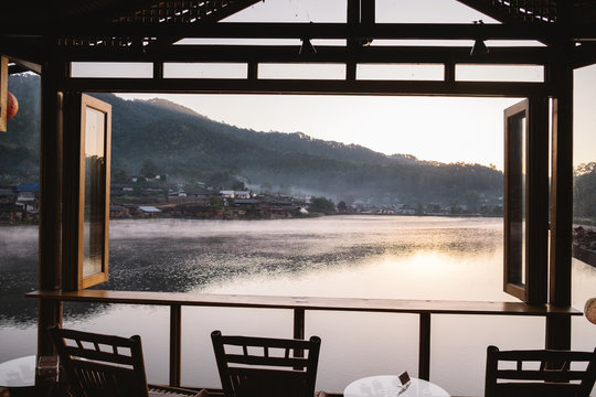 Mountain Mist and riverside view from the wooden window and chair of Little Home at Ruk Thai in Mae Hong Sorn Province, Thailand. Morning sunrise 