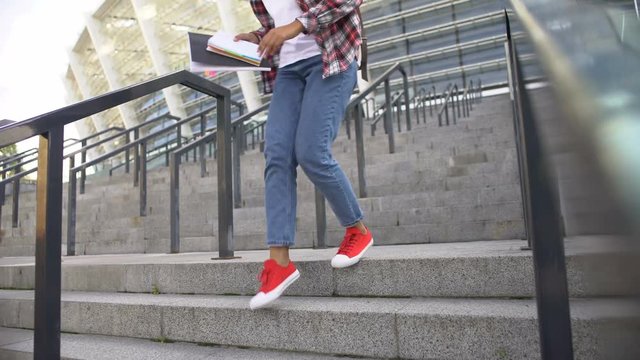 Young african american woman running down stairs, student hurrying to classes