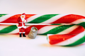 close up mini santa and the bag of gift. over the candy background. Christmas decoration.