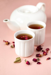 Herbal tea with roses on pink background