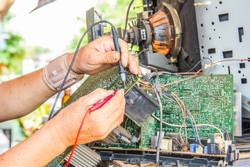 technician using voltage meter for voltage measurement in old television