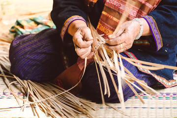 Eldery Thai woman weaving the bamboo basket.