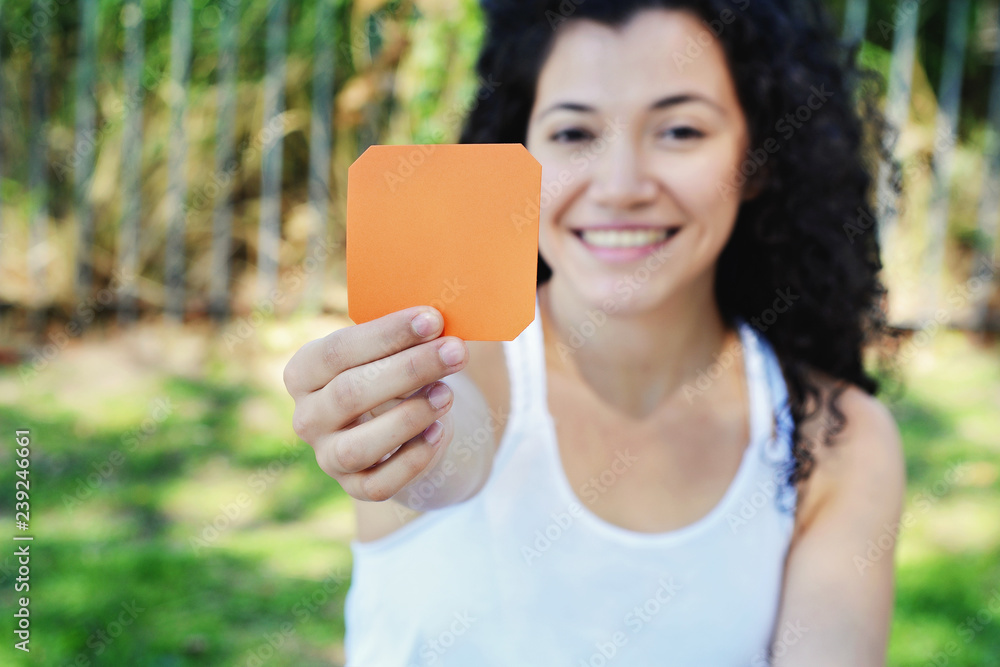 Wall mural Woman outdoors showing a blank notepad.