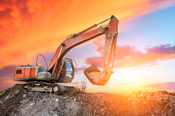 Excavator in construction site on sunset sky background