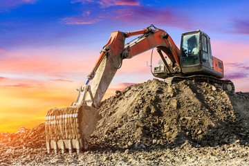 Excavator in construction site on sunset sky background