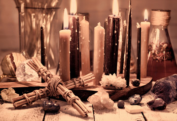Vintage still life with cross, black candles, minerals and flasks on table. Magic ritual. Wicca,...