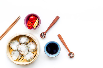 Chinese food set with dim sum, sticks and tea on white background top view copy space