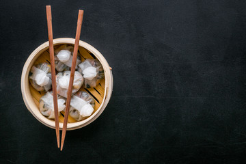 Dinner in Chinese restaurant with dim sum, sticks on black background top view space for text