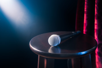 microphone on a wooden stool on a stand up comedy stage with reflectors ray, high contrast image - obrazy, fototapety, plakaty