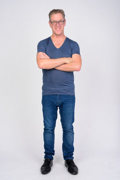 Full Body Shot Of Happy Mature Man Smiling With Arms Crossed Against White Background