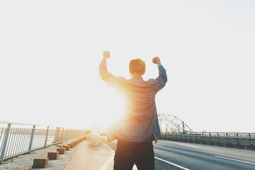 Happy man is standing with his arms raised up