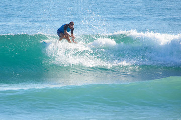 man in the ocean on a surfboard rides on top of a wave