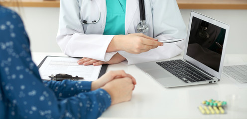  Close-up of a doctor and  patient  sitting at the desk while physician pointing into laptop computer. Medicine and health care concept