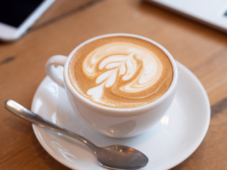 coffee latte in a white cup on wooden table in coffee shop.