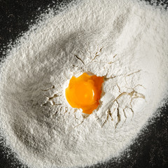 Heap flour yolk black background top view